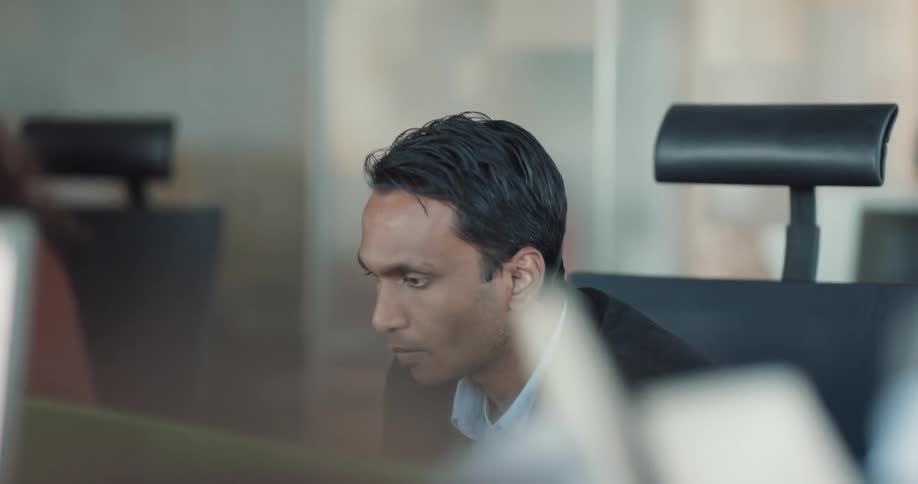 Young man sitting on his chair in the office space talking to his coworker and drinking a cup of coffee