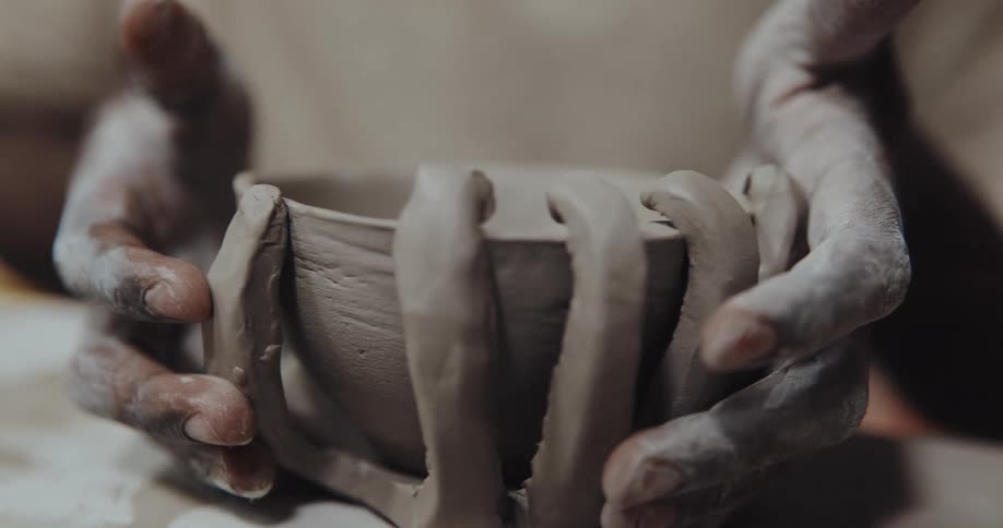 Potter shapes artistically detailed bowl from clay