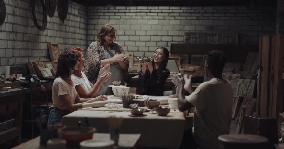 A woman shows off her sculpture and everyone claps
