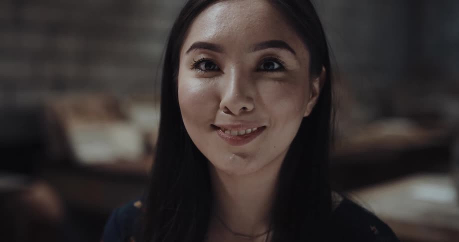 A woman is sitting indoors and is smiling