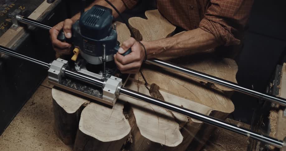 A man is leveling off the top of an oddly shaped log