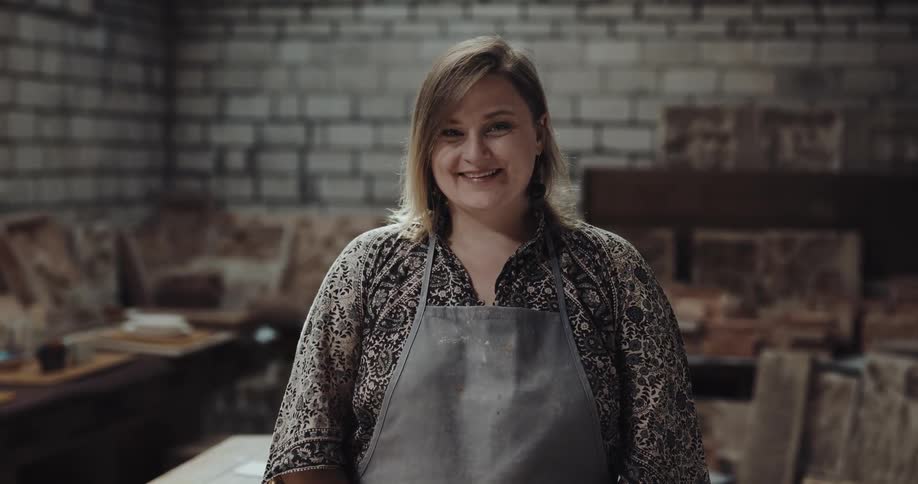 Female crafter stands in workshop smiling
