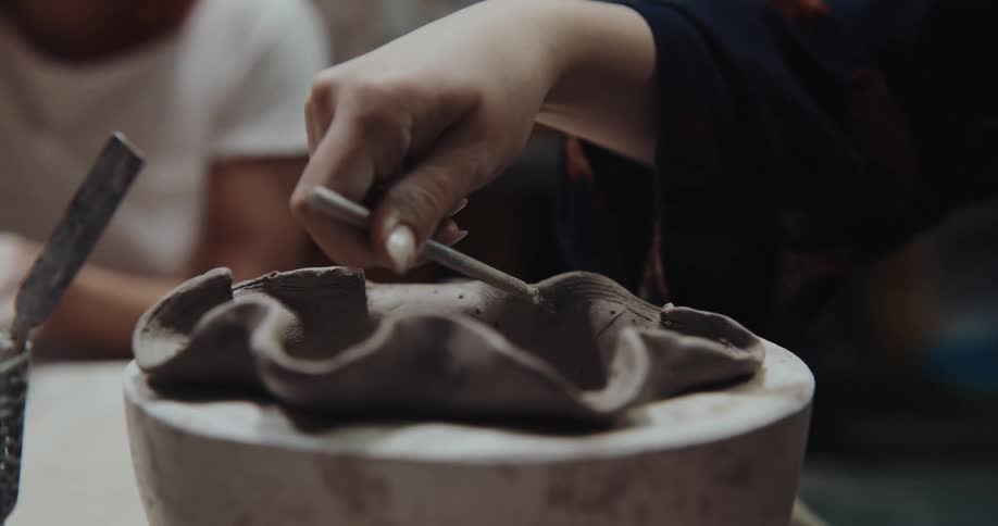Women are sitting at a table sculpting with clay
