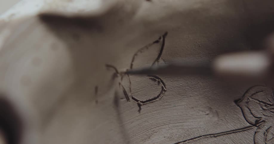 A person is using a tool to carve a butterfly