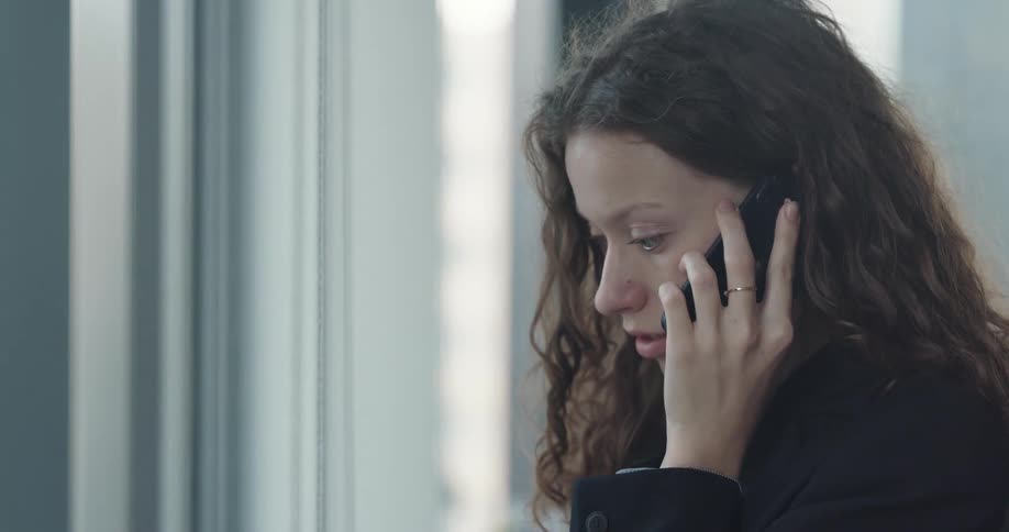 A woman is in her office and talking on her cell phone
