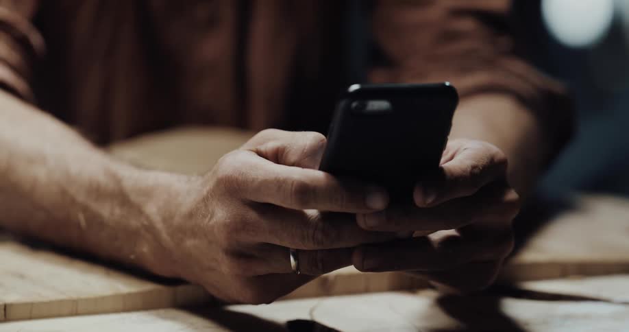 A man is texting on his cellphone indoors