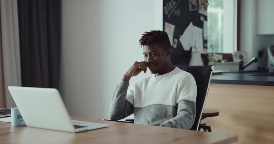 A man is typing on his laptop and sitting at a table