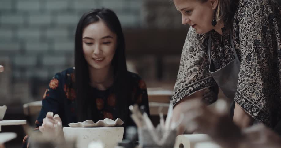 A group of people are in a pottery class sculpting with clay