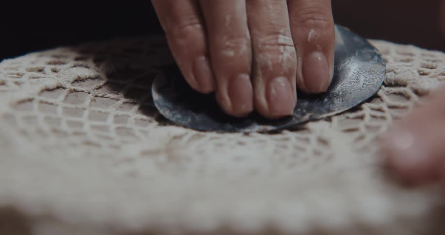 A person is pressing cloth on a sculpted plate