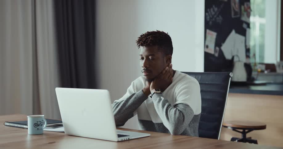 A man is typing on his laptop in his house