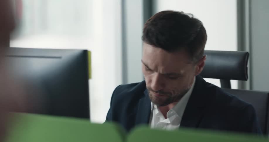 A man is sitting at his office desk near a computer