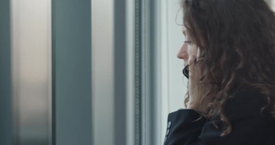 A woman is in her office and talking on a cellphone