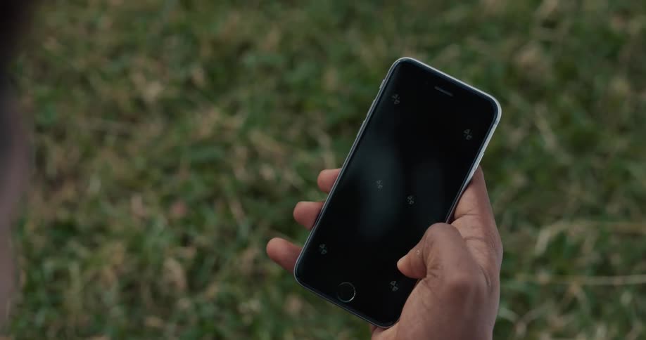 Mans hand uses smartphone sitting on lawn