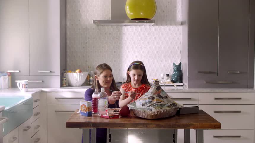 A woman and child paint an art project on the table