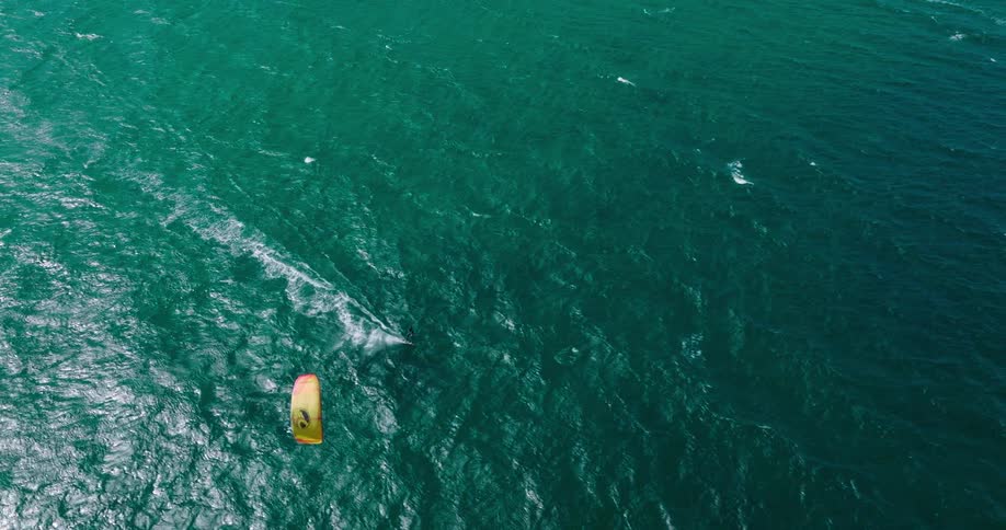 Aerial view of a person kitesurfing on the deep green surface of the ocean