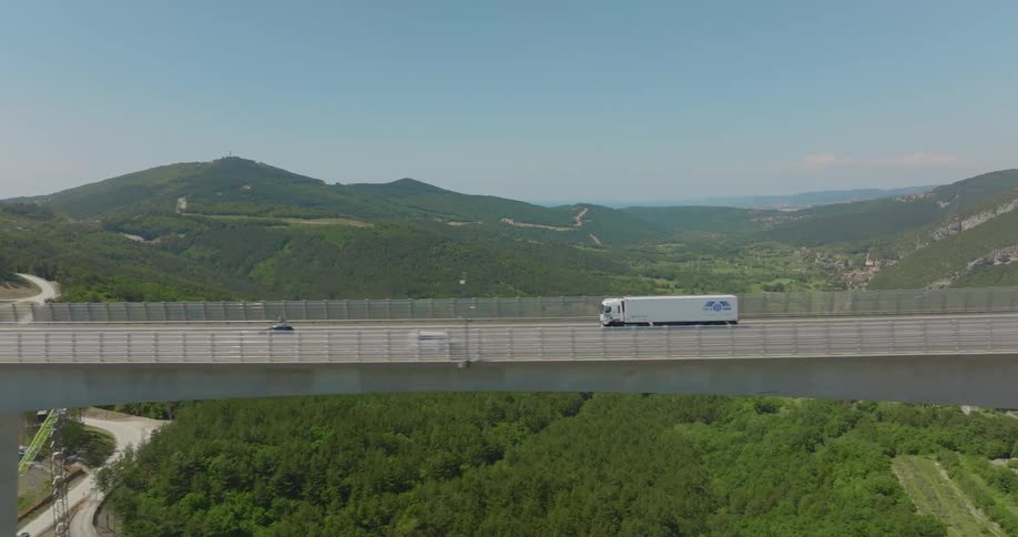 Aerial view of cars driving on a bridge is displayed