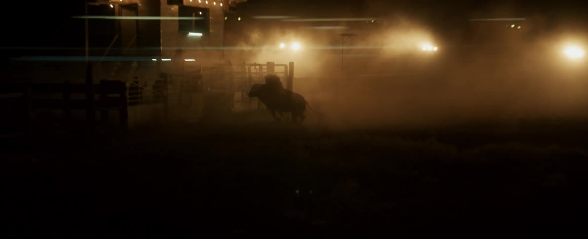 Man climbs over fence to evade bucking bull being ridden by cowboy at night