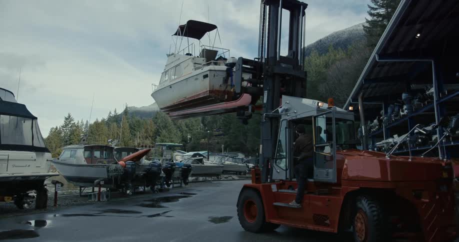 A marina forklift carries a boat from its berth