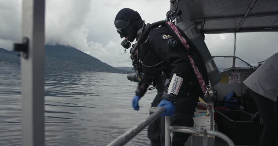 A female technical diver enters the water with full gear