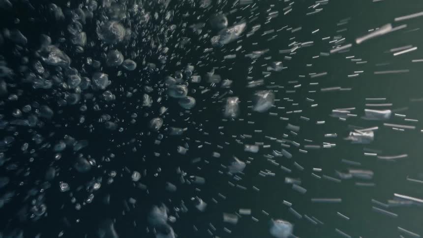 POV descending into the ocean with bubbles