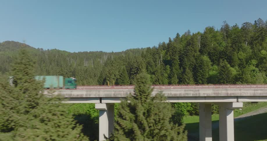 Trucks and cars are driving over a bridge in a rural area
