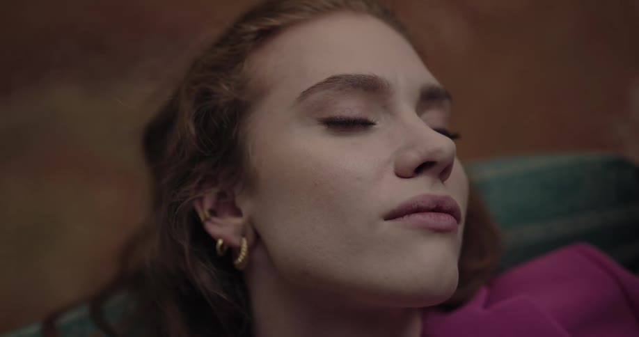 A woman is resting and laying on a couch