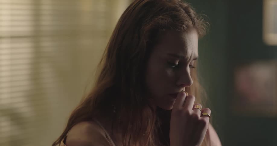 Young woman standing indoors with a thoughtful and sad facial expression