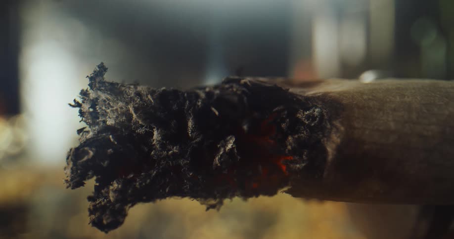 Cigarette tip burns and turns to ash releasing smoke