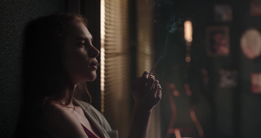 Young female leaning on wall smoking a cigarette
