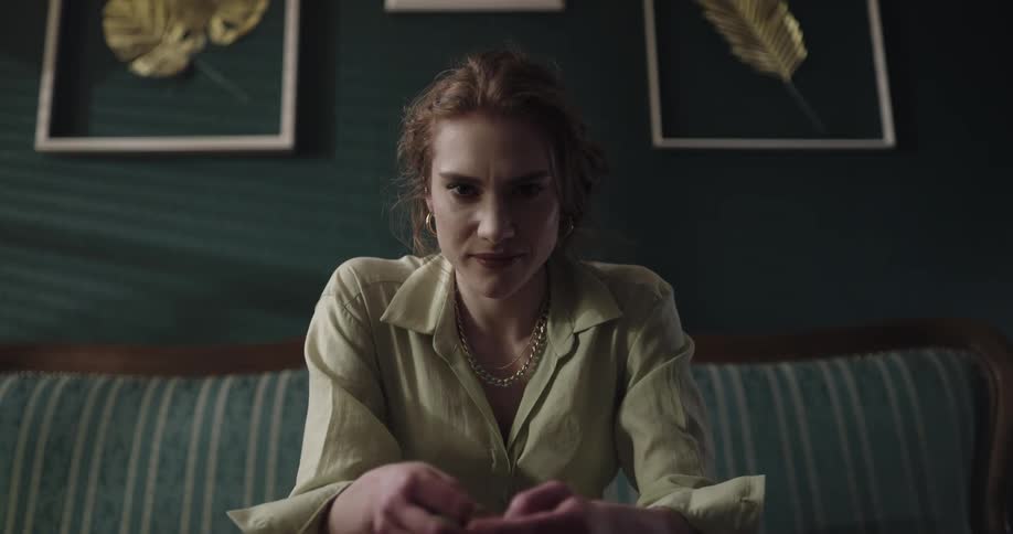 A female is sitting on a couch during the daytime