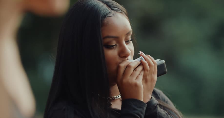 Young woman playing the harmonica surrounded by dancers on a park