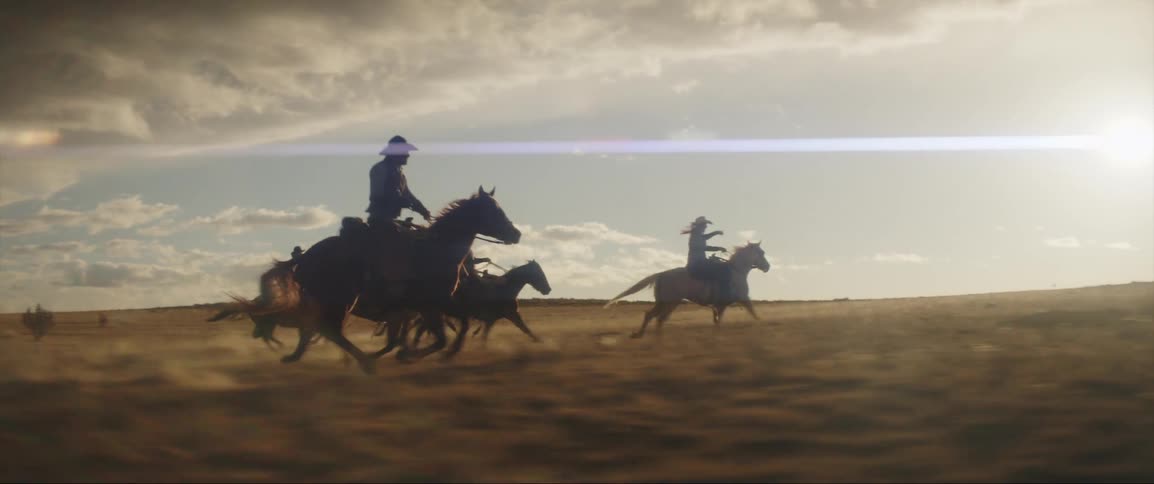 A group of men are riding horses through the wild west