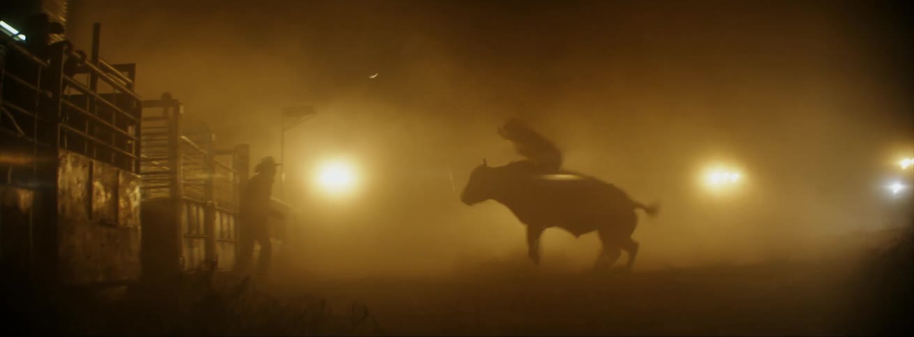 Bull rider falls off bucking bull in arena at night