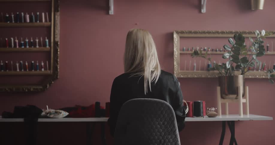 Woman uses pins and selects thread in preparation to using sewing machine