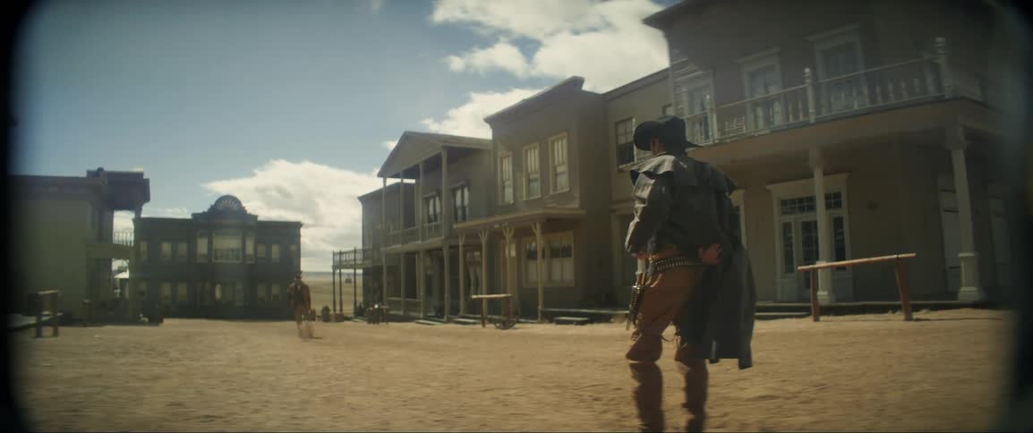 Two cowboys face each other in a gunfight in the street of an old west town
