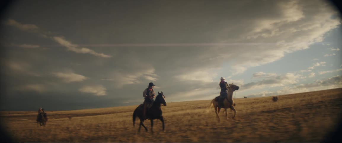A group of men are riding horses through a rural area