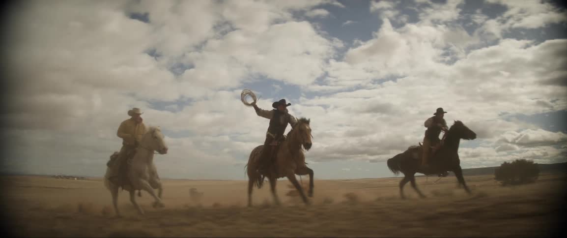 A group of men are riding horses in a grassland area