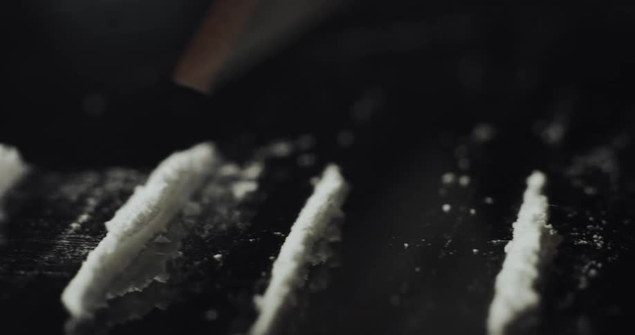 Someone is making lines of cocaine on a mirror with a credit card