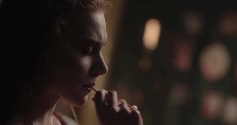 Distressed young redhead woman lighting up a cigarette and then smoking it