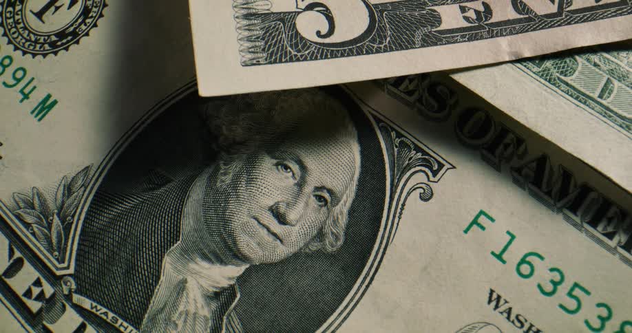 American paper currency in various denominations lies scattered