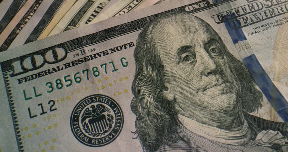 A one hundred dollar bill sitting on top of a stack of other bills