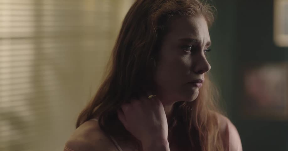 A woman is standing in her home and looks sad