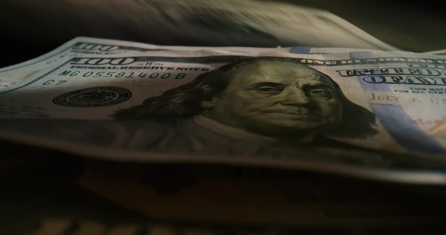 Multiple currency bills are being placed on display