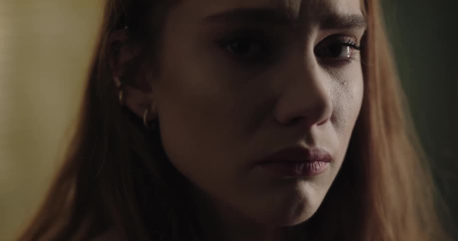 An upset woman turns her head to look into the camera