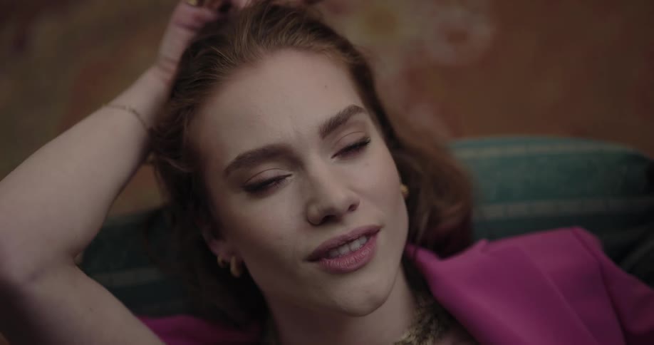 Young beautiful redhead woman lying on the couch thinking about life and smiling