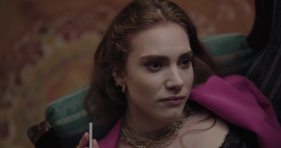 Young beautiful woman lying on the couch with a thoughtful facial expression holding a cigarette