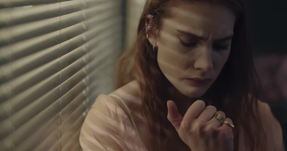 Young woman standing near the window with a sad and anxious looking face