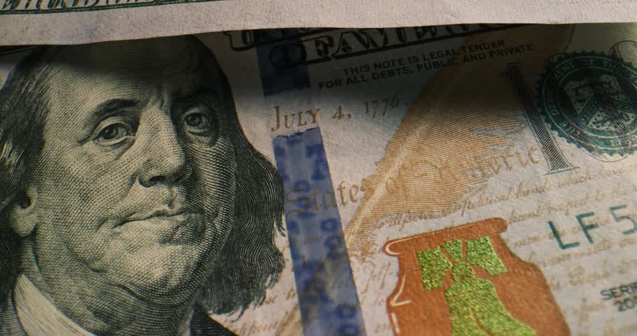 A stack of one hundred dollar bills rest on a table