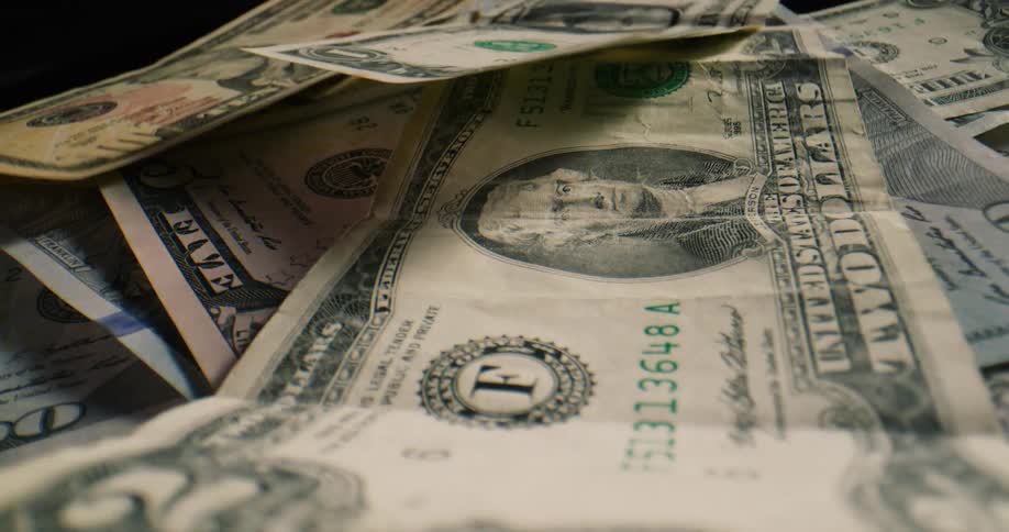 American banknotes fall onto a surface one by one