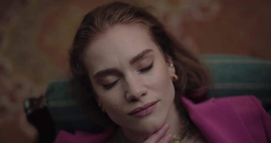 Woman leisurely resting reclined on a couch next to an elaborate rug